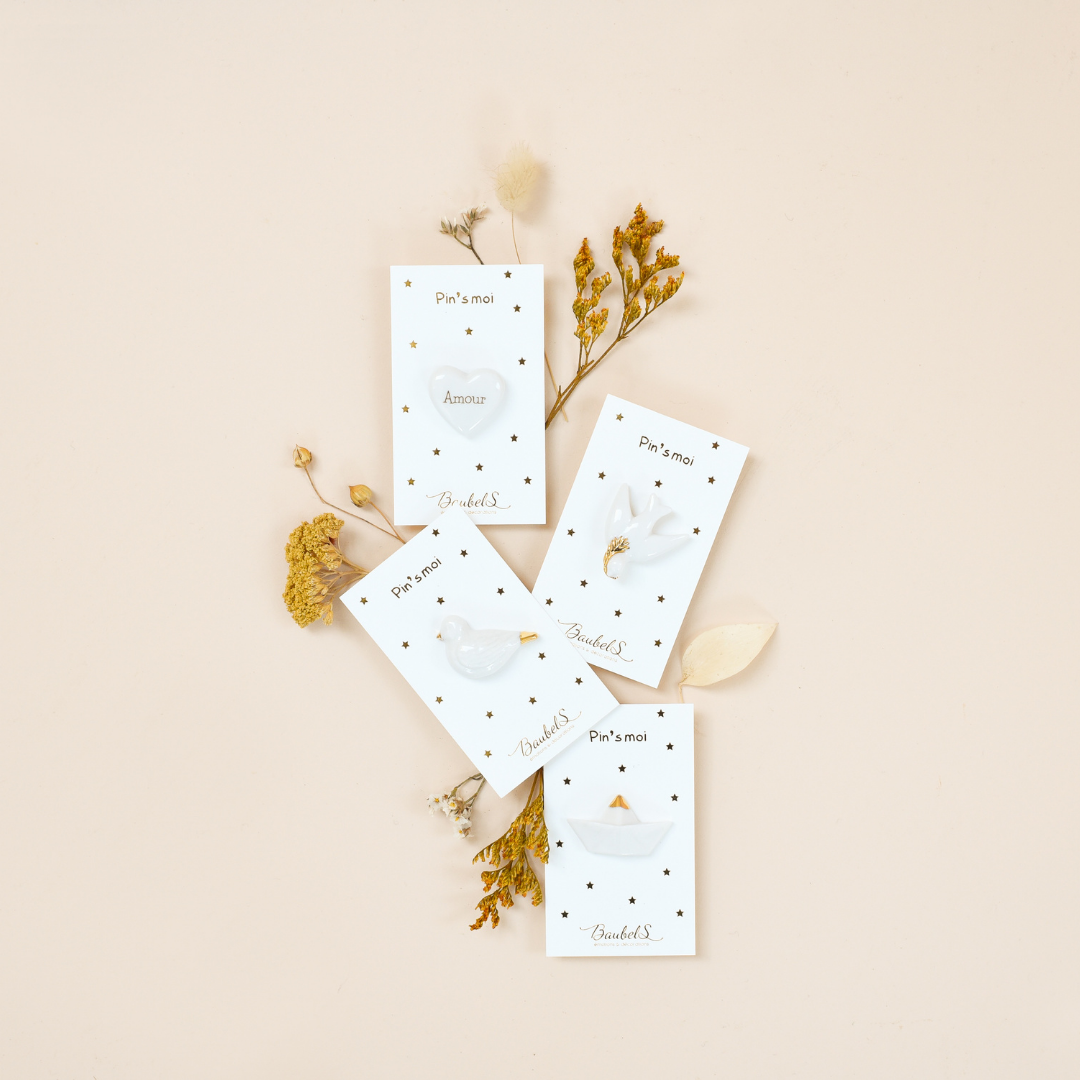 Photo plusieurs pins ou broches de la collection blanc et doré, de la marque Baubels.