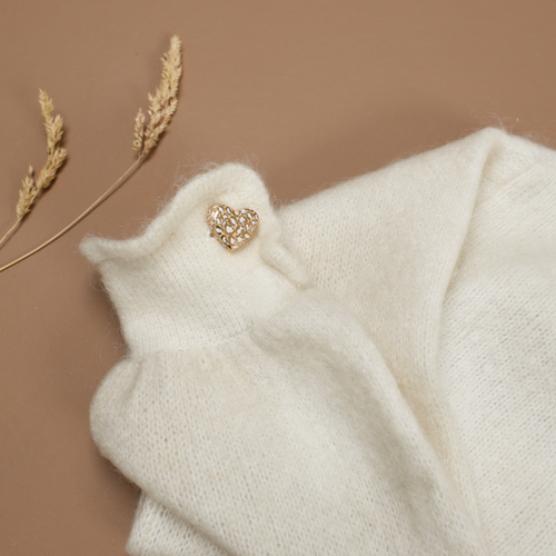 Photo d'un pins ou d'une broche en forme de coeur. Le motif Léopard y est inscrit en couleur blanc et doré, de la marque Baubels