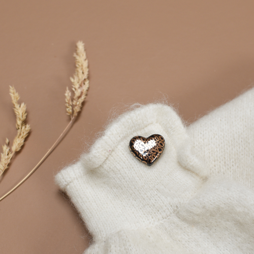 Photo d'un pins ou d'une broche en forme de coeur. Le motif Léopard y est inscrit en couleur noir et doré, de la marque Baubels